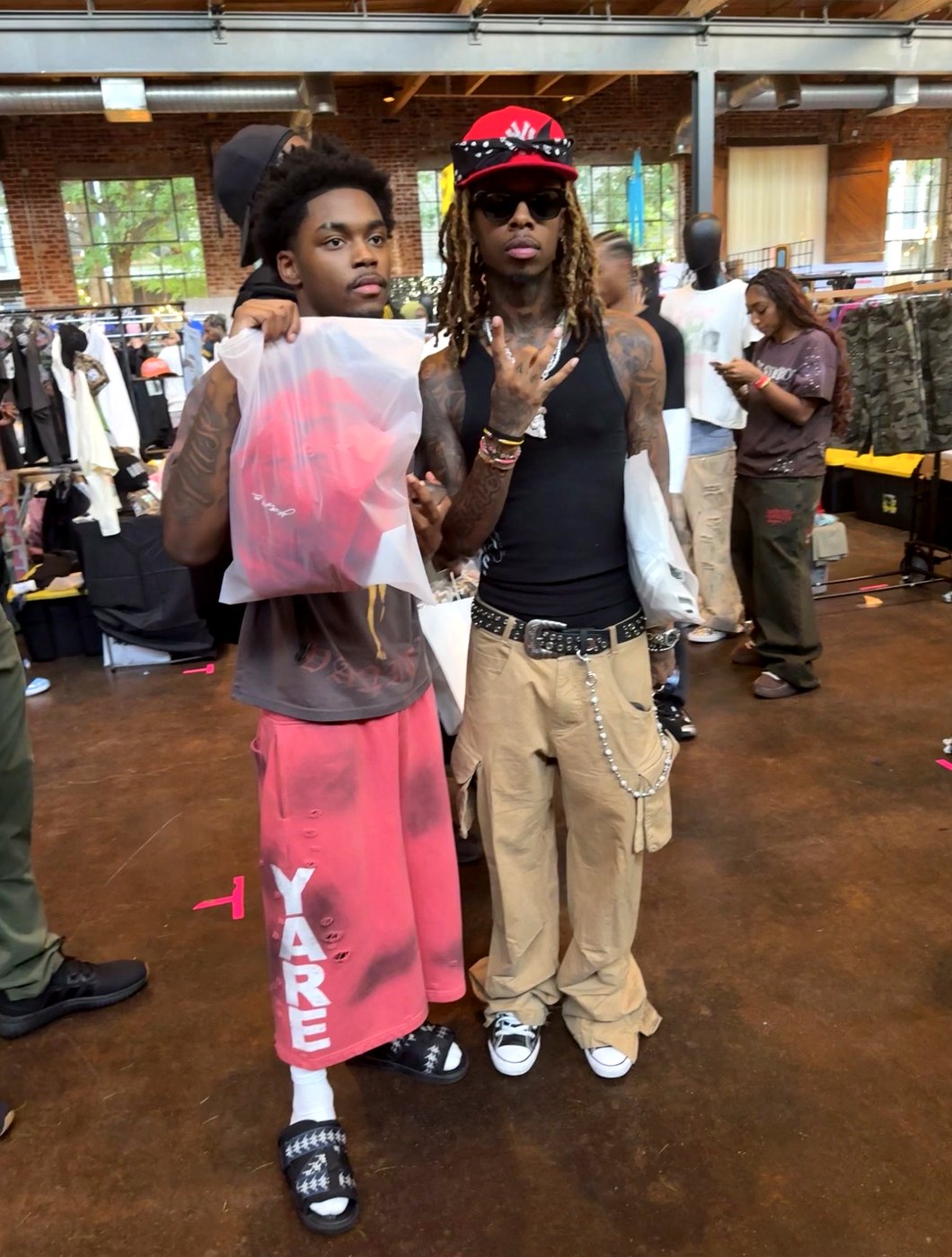Elijah Cox holding a bagged red YARE piece on the floor of the Unfazed Streetwear Market in Atlanta