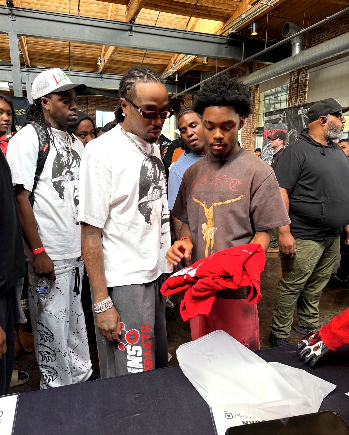 Elijah Cox showing a folded red YARE jacket to shoppers at the YARE table during the Atlanta streetwear market