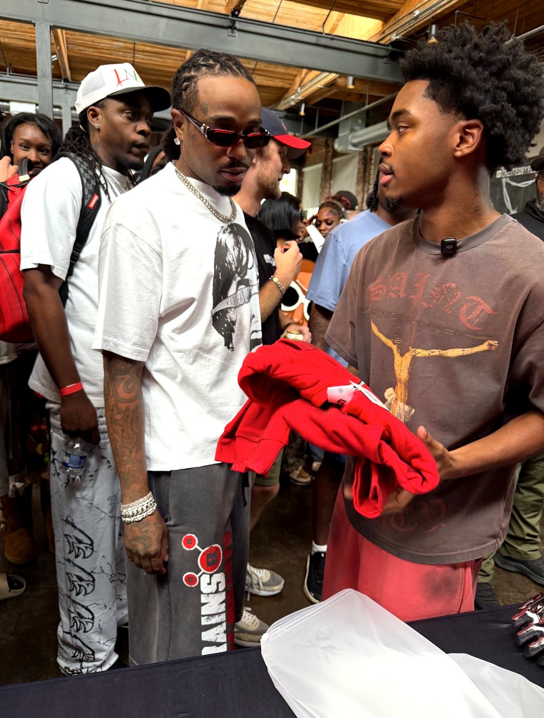 Elijah Cox talking with shoppers while holding red YARE pieces at the Atlanta streetwear market