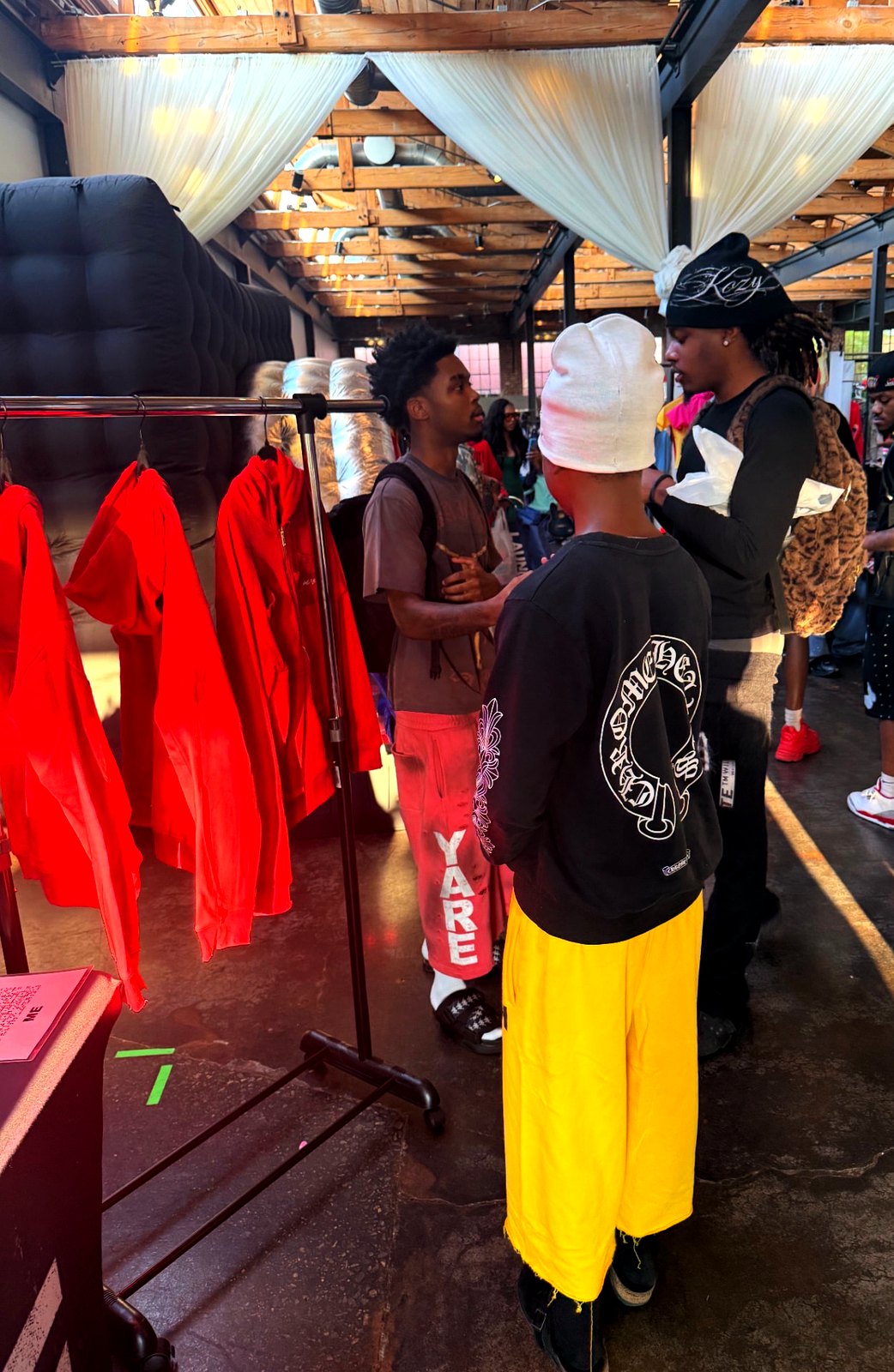 A rack of red YARE jackets and YARE sweats worn by a shopper at the market