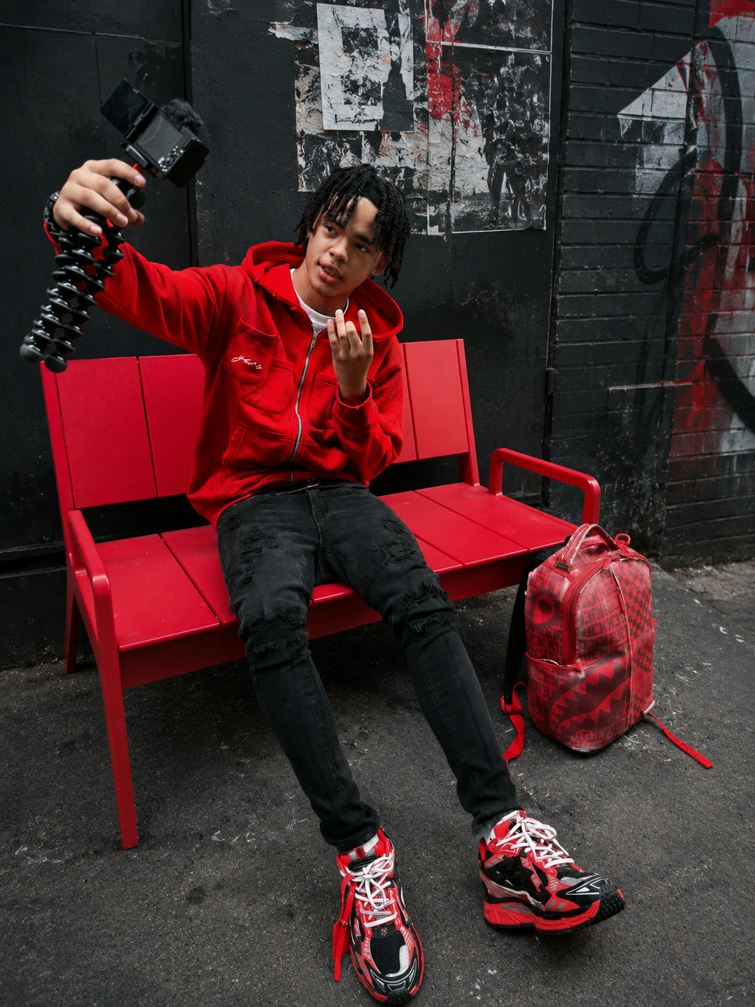 Young man seated in the red Double Pocket YARE Jacket styled with black denim